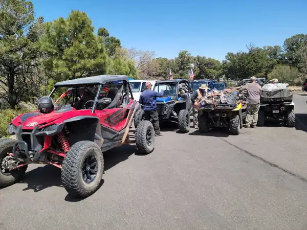 A red side-by-side and other machines parked while riders get ready to head out